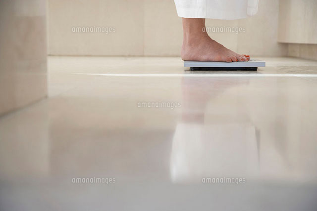 Mature woman standing on scale in bathroom weighing herse
(c)moodboard