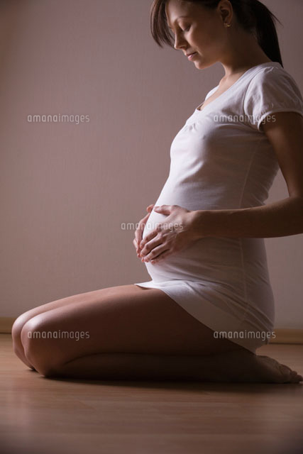 Pregnant woman kneels looking down holding stomach
(c)moodboard