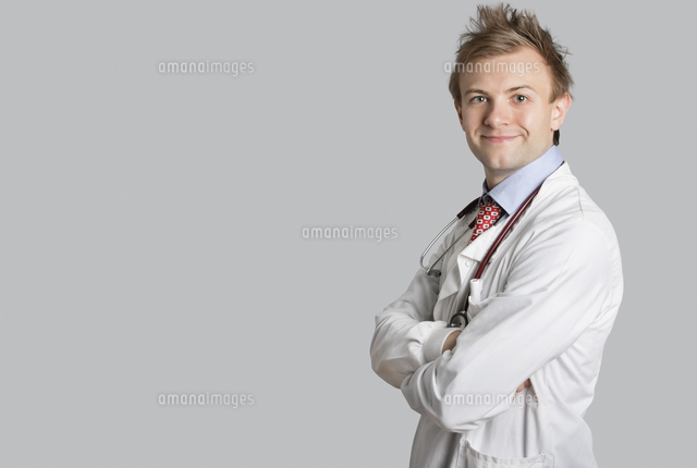 Portrait of a male doctor smiling with arms crossed over gra
(c)moodboard