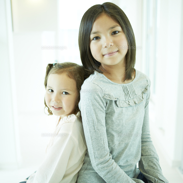 背中合わせに寄り添う2人の女の子 の写真素材 イラスト素材 アマナイメージズ