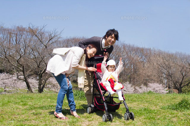 乳母車の赤ちゃんと公園を散歩する3人家族
(c)iconics