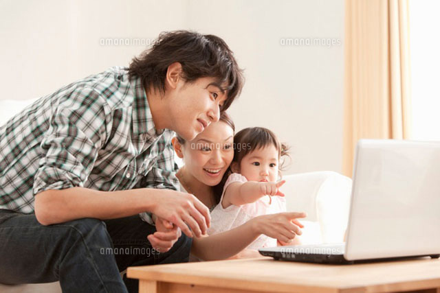 パソコンの画面を見つめる赤ちゃんと若い夫婦
(c)iconics