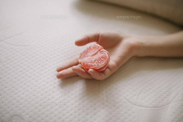 Cropped hand of woman holding grapefruit on bed at home
(c)Cavan Images