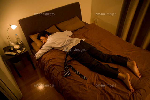スーツを着たままベッドで眠るビジネスマン
(c)DAJ