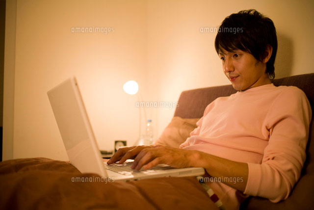 ベッドでパソコンのキーボードを打つ男性
(c)DAJ