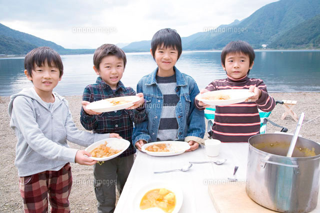 湖畔でカレーライスを持って喜ぶ4人の男の子
(c)Tomozo/a.collectionRF