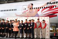 自身の姿が描かれた航空機の前で、客室乗務員らと並ぶ浅田真央選手(左中央)=2013年12月25日、東京都大田区