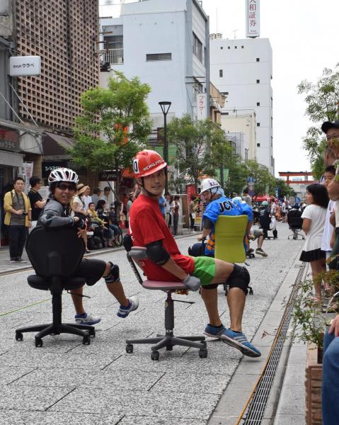 横向きや後ろ向きになって疾走する「いす―１グランプリ」の参加者＝福山市