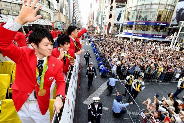 パレードで沿道に集まった大勢の人たちに手を振る体操の内村航平選手(左)ら=2016年10月7日、東京・銀座、代表撮影