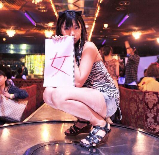 「女」の文字を手にし、ポーズを取る=モカさん提供