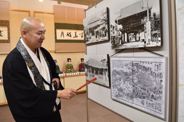 伊勢参宮名所図会を見ながら、津観音の「鬼押さえ節分会」について説明する第28代住職の岩鶴密伝さん=2021年1月28日、津市大門