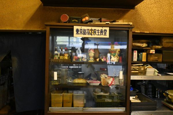おかずを入れる棚に「民生食堂」と書かれた札がぶら下がっています