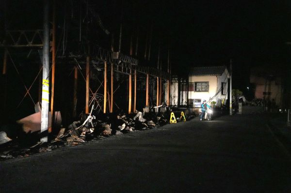 火災で焼けた建物の前で新聞配達をする配達員