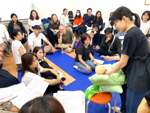 助産師の実演に見入る参加者。椅子が足らなくなるほどの盛況ぶりで、通訳ボランティアと父親は床に座った