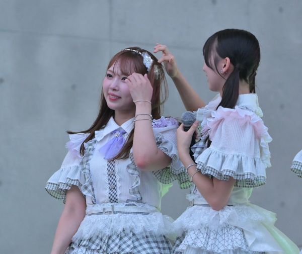 あいさつの途中、山内さんの髪を整える渋井さん=2025年7月、東京・お台場