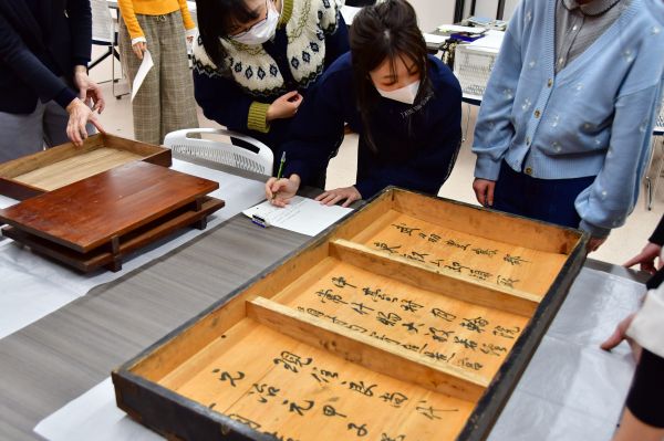大般若経が入っていた箱に書かれた文字を調査する学生たち
