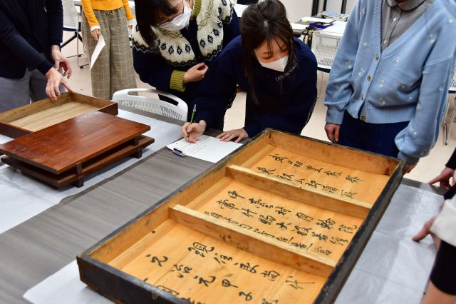 箱に書かれた文字を調べる学生たち