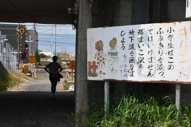 踏切近くに、小学校が設置している看板。死亡した2人は写真手前側から奥へ進み、踏切に入ったと兵庫県警はみています=2025年7月、神戸市垂水区、原野百々恵撮影