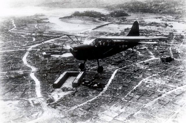10・10空襲で焼け野原になった那覇市街の上空を飛ぶ米軍偵察機＝「写真集那覇百年のあゆみ」掲載、那覇市歴史博物館所蔵