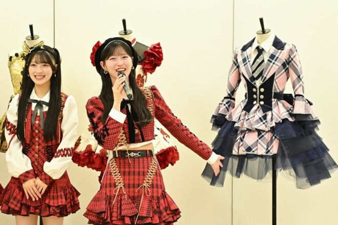 茅野しのぶさんが手がけた衣装展。前田敦子さんが東京ドームでのコンサートで着た衣装を「大好きな衣装」と紹介しながら、笑顔を見せるAKB48の八木愛月さん(中央)=2025年10月、東京都千代田区、いずれも松村北斗撮影