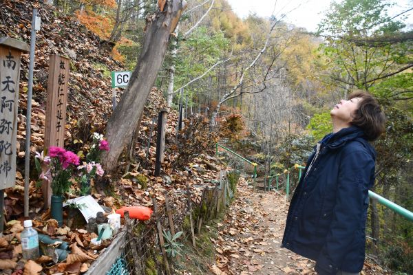 能仁さんの墓標の前で空を見上げる山上優さん

