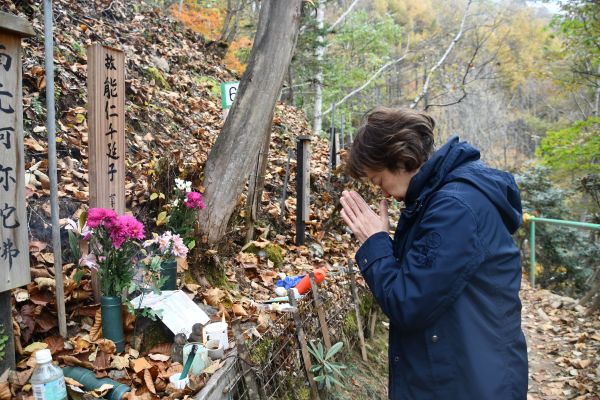 能仁千延子さんの墓標に手を合わせる山上優さん