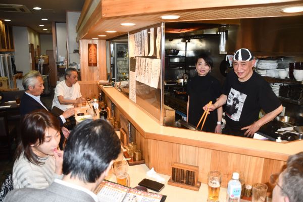 カウンターの中で料理を作る吉岡富佐男さん（手前）とかつ江さん。本間さんはいつもカウンターの左端に座っていた