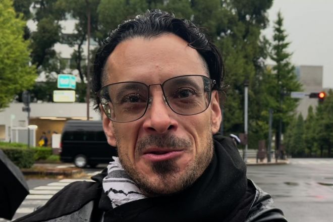 移民政策反対デモの様子を見ながら取材に応じるエィヴェリー・フェーンさん＝2025年10月26日、東京都千代田区