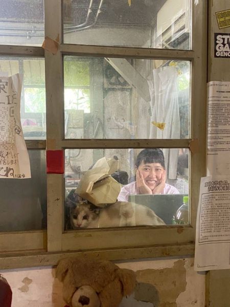 吉田寮現棟の玄関にてネコと写る板谷めぐみさん