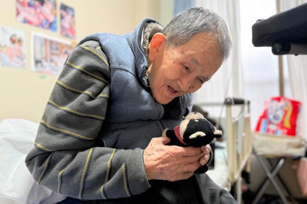 声を再生してくれるぬいぐるみ「ごんた」がお気に入り。「ごんた、お客さんや」と声をかけ、再生した声を記者に聞かせてくれた=2025年12月4日、北九州市八幡東区、山下知子撮影