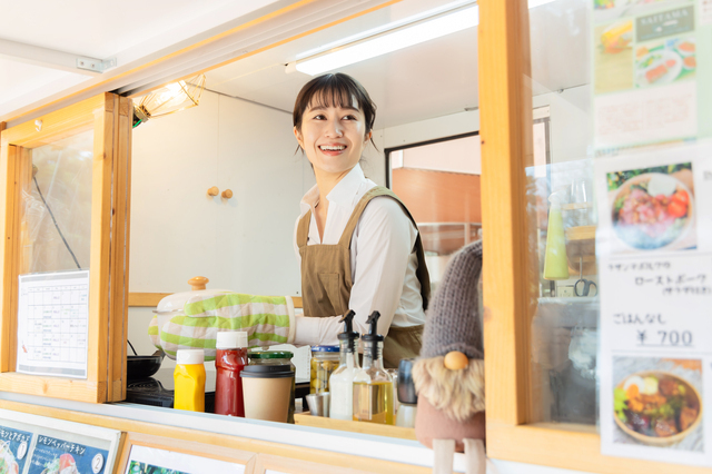 キッチンカーから外を眺める女性