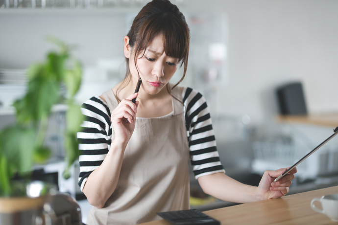 悩むエプロン姿の女性