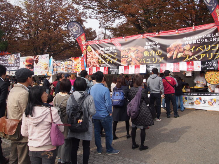 「フィエスタ・デ・エスパーニャ2018」の開催会場は、東京の代々木公園。大規模イベント開催場所の メッカとして知られています。 「フィエスタ・デ・エスパーニャ2018」のイベントの開催は午前10時から。オープンを待ち望んでいた多くの方々が、スタートと同時にお目当てのブースに並びはじめました。そして1時間もしないうちに会場のテーブル席は来場者でいっぱいになりました。 飲食関係のブースは、約30店舗。開場にあわせてすぐに提供できるよう早めに調理をしていたところが多く、そこかしこから美味しそうな香りがしてきます。