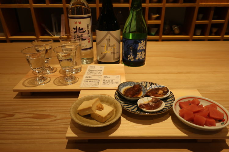 3種類のお酒の飲み比べセットとおつまみ。 おつまみは左から「五箇山豆腐の麹味噌漬け」「ほたるいか三種盛」「赤カブの漬物」。