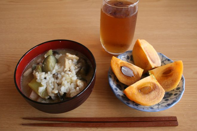 夕飯の残りで作った雑炊と、稲刈りの最中にもいでもらった柿の朝ごはん