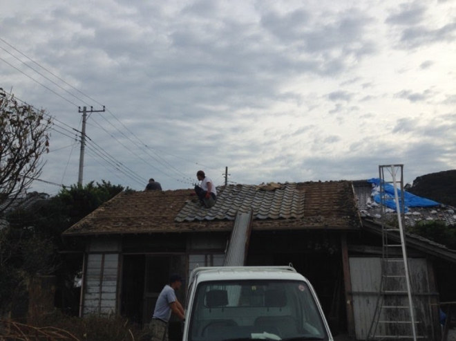 台風により損傷した納屋の屋根。皆で力を合わせて瓦を下ろす