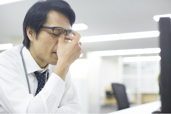 目をおさえる男性
